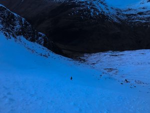 Chris a way ahead descending a snowy mountain after dusk.