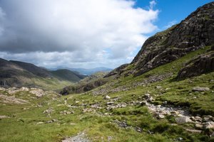Looking down a long green valley. A stone path winds from the right.