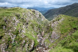 A small crevasse in the hillside, with a stream running through the middle.