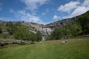 The face of Malham Cove as seen from a distance on a sunny day.