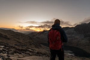 Ed facing away from the camera just before sunrise. He’s got a bright backpack on.