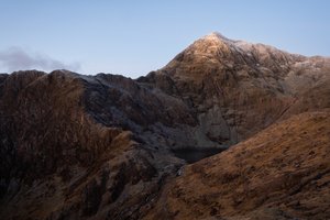The jagged face of snowdon before sunrise. The mountain has a light dusting of snow on the top.