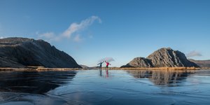 Ed and Chris pose on the other side of a small pond with arms outstretched. The pond is frozen with crystals extending over the surface.