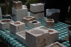 A bunch of slip-cast moulds on a table, several filled with liquid clay.