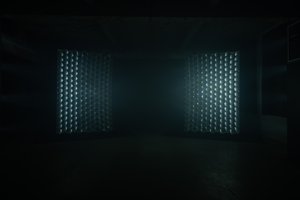 In a dark room, facing straight on to two very large reflective panels, each made up of hundreds of lenses or mirrors.