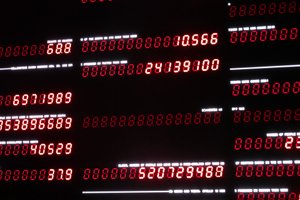 A dark photo with multiple lines of old fashioned seven-segement displays with red LEDs. Some lines are faintly lit whilst others show numbers.