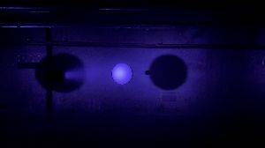 A purple light spins horizontally around a white sphere in the centre making it look like a moon.