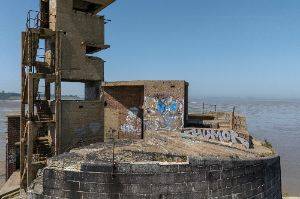 Photo of the roof of part of the battery, showing the concrete tower and stairs and some graffiti on the walls.