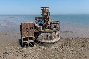 Exterior photo of the battery showing a rectangular structure on stilts on the left, and a larger cylindrical structure on the right.