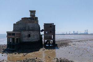 Exterior photo of the battery, largely in silhouette, with industry visible in the background.