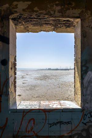 Looking out a decaying window to muddy estuary beyond.