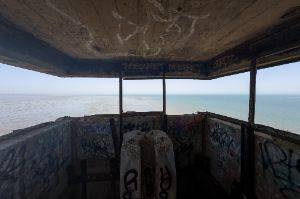 Photo taken from within a small room with exposed opening on all side - a panoramic view of the channel and eastuary.
