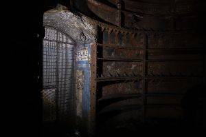 Dimly lit doorway with sign to stairs and metal bulkheads to the side