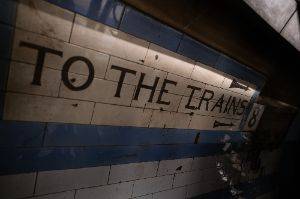A sign painted on some old cream tiles reads ‘to the trains’
