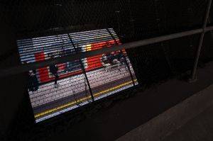 A pitch black room with vent that lets you see a tube platform