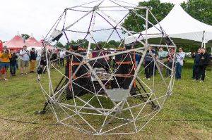 Large geodesic sphere in front of a robotic machine