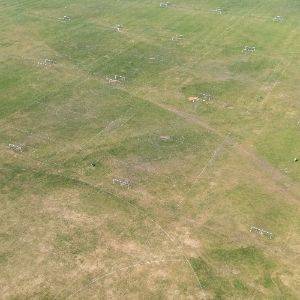 Drone photo looking over a empty large grass field filled with football pitches.