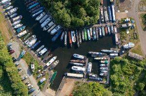 Drone photo looking straight down at a canal boat mooring. There’s dozens of boats all lined up side by side.