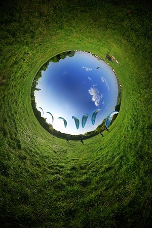 Reverse stereographic panorama of a hand-glider taking off from grass.