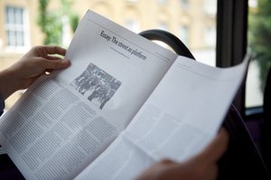 Photo of a PaperLater newspaper being read on a bus.