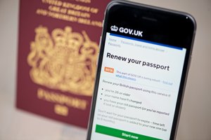 Photo of the passport renewal service on a phone, in front of a UK passport.
