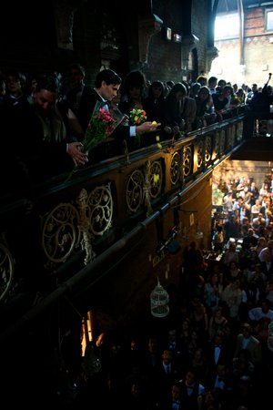 A man drops yellow flower petals over a balcony.