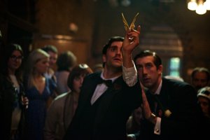 A man holding an origami paper bird, followed by other people.